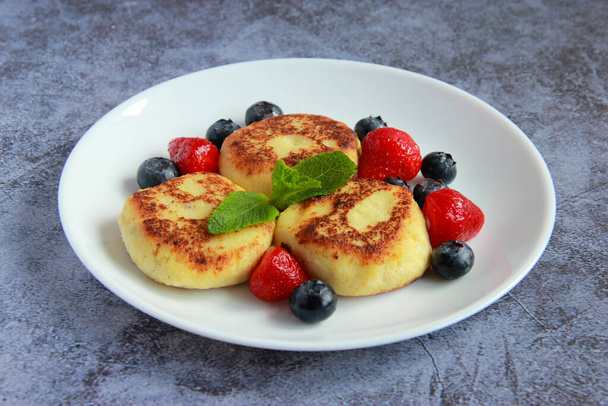 Vegan syrniki made of tofu. Homemade tofu cheesecakes syrnyky decorated with fresh berries. Healthy vegan breakfast. - 写真・画像