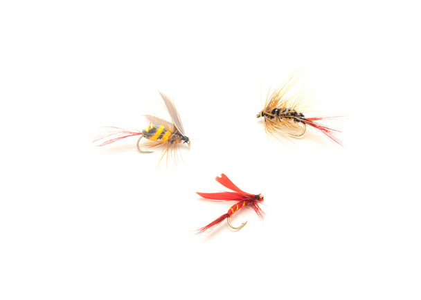 Drei Fliegenfischköder in verschiedenen Feilen, Farben und Hakengrößen isoliert auf weißem Hintergrund. Sortiment trockener, nasser, handgebundener Leichtgewichtsfliegen mit scharfen Kohlenstoffstahlhaken - Foto, Bild