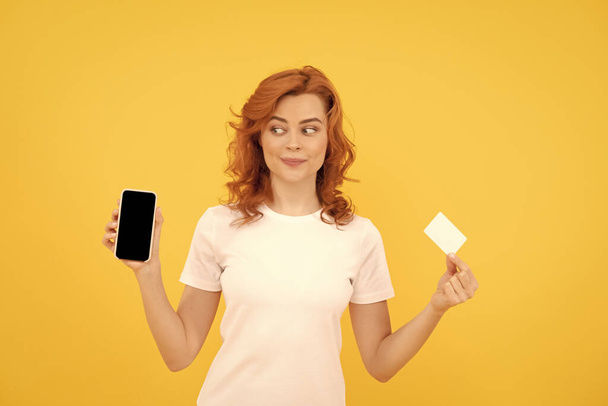 mujer alegre mostrando tarjeta de crédito o débito y teléfono inteligente para hacer compras en línea, lunes cibernético. - Foto, Imagen