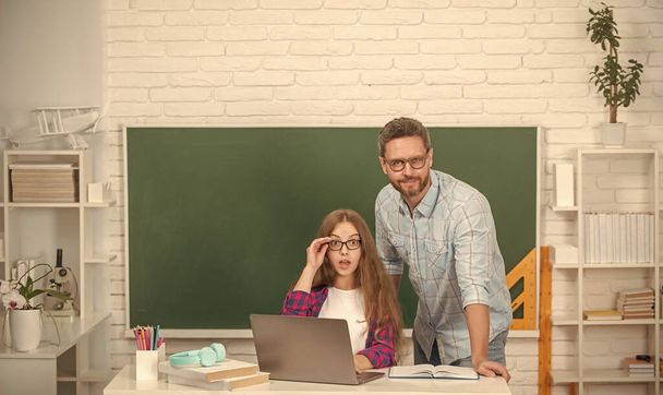 étude étonnante de père et d'enfant à l'école avec ordinateur portable sur fond de tableau noir, e-learning - Photo, image