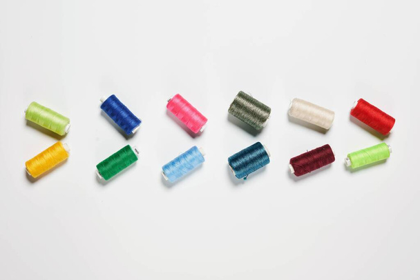 Rows of colorful thread spools on white - Фото, зображення