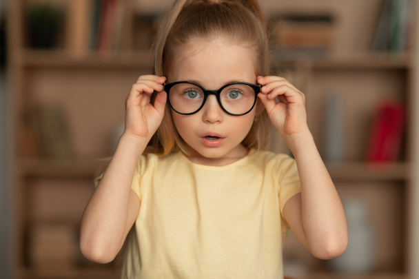 Szemüveges kislány, akinek rossz a látása, otthon pózol. - Fotó, kép