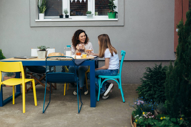 caucasian mother and daughter enjoying breakfast together at home in back yard - Zdjęcie, obraz
