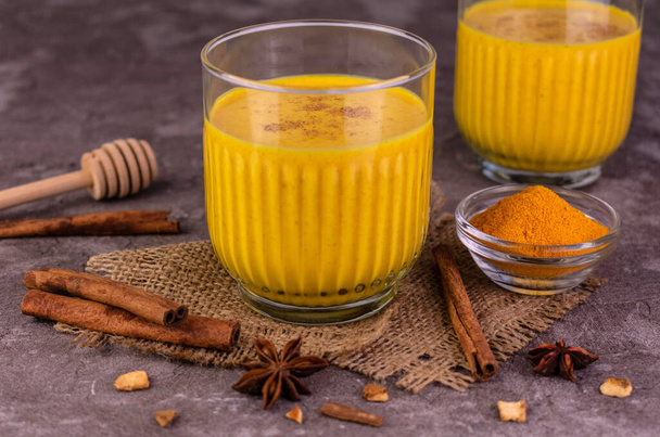 Latte with turmeric. Golden milk with cinnamon and spices. Healthy vegan drink - Photo, Image