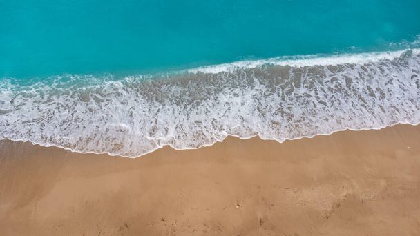 Aerial view of beautiful sandy beach and soft turquoise ocean wave. Tropical sea in summer season on Megali Petra beach on Lefkada island. - Photo, Image