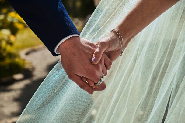 Hands intertwined with a wedding dress in the background. Just Married - Foto, Imagem