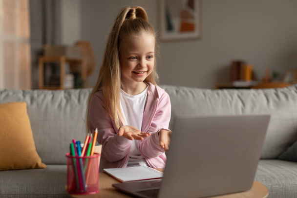 Little Schoolgirl Video Calling Using Laptop Having Online Lesson Indoor - Foto, Imagen