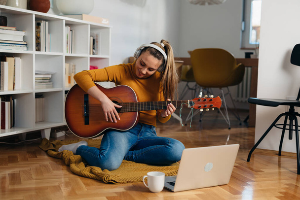 young woman learning to play guitar at home - Фото, зображення