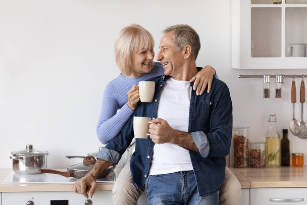 Loving elderly couple enjoying morning coffee at home - Fotó, kép