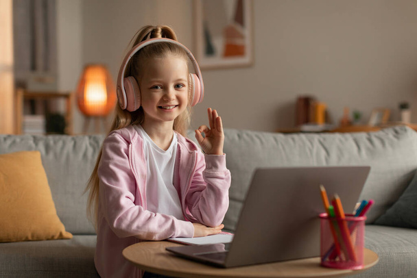 Little Girl Using Laptop Gesturing Okay Learning Online At Home - 写真・画像
