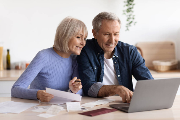 Feliz pareja de ancianos pagando facturas en línea, usando computadora - Foto, Imagen