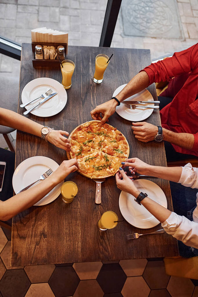 Close up view of people that taking and eating pizza indoors together. - Foto, immagini