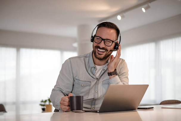 Cheerful young adult businessman entrepreneur freelancer making online video call. Portrait of man working from home office providing call support call center operator. - Valokuva, kuva