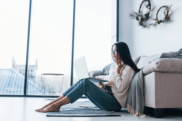 Young beautiful woman in glasses sitting at home alone with laptop. - Foto, Bild