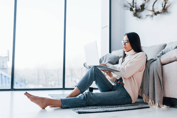 Young beautiful woman in glasses sitting at home alone with laptop. - 写真・画像