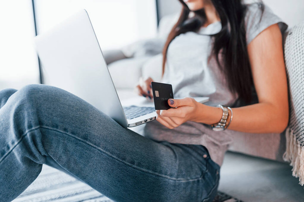 Close up view of woman in casual clothes that sitting at home alone with laptop and credit card. - Foto, immagini