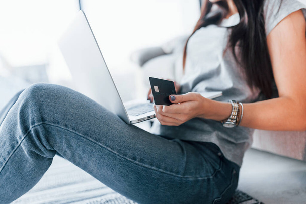Close up widok kobiety w ubraniach casual że siedzi w domu sam z laptopem i kartą kredytową. - Zdjęcie, obraz
