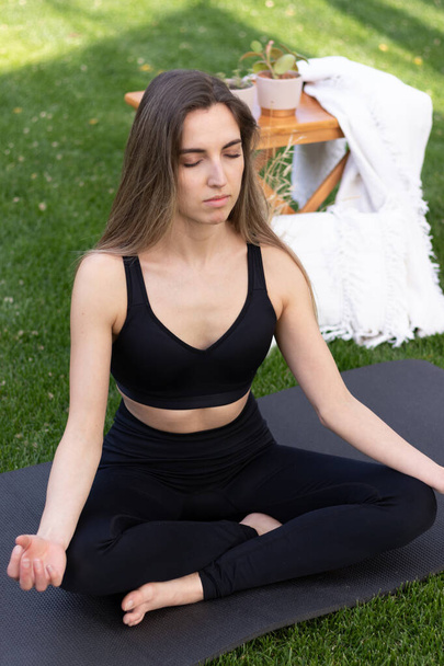 Baharda bahçede meditasyon yapan genç ve güzel sarışın bir kadın. Arkasında da boho masası var. - Fotoğraf, Görsel