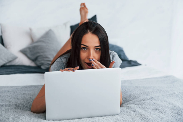 Young beautiful woman in casual clothes lying down at home alone with laptop. - Foto, Bild