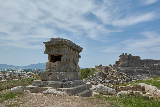 Lycian Tomb ve starožitném městě Xanthos se starobylým amfiteátrem na pozadí, Turecko - Fotografie, Obrázek