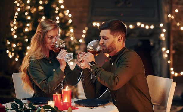 Drinks wine. Young lovely couple have romantic dinner indoors together. - 写真・画像