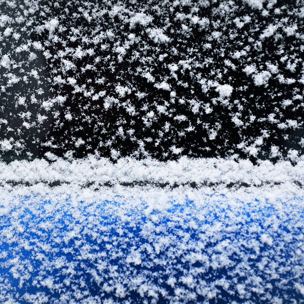 Snowflakes on a car window after a blizzard, close-up. Cold weather, winter, climate change, cleaning and care, dangerous driving concepts - Photo, Image
