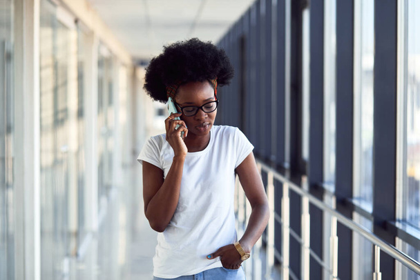 Young african american female passanger in casual clothes is in airport with phone. - 写真・画像