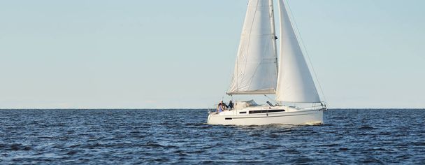 Bílá šalupa manipulované jachty plachtění v Baltském moři při západu slunce. Jasná obloha po bouři, měkké sluneční světlo. Doprava, cestování, plavba, sport, rekreace, volný čas, závodní, regata - Fotografie, Obrázek