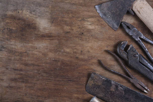 Viejas herramientas de construcción oxidadas sobre una mesa de madera marrón  - Foto, imagen