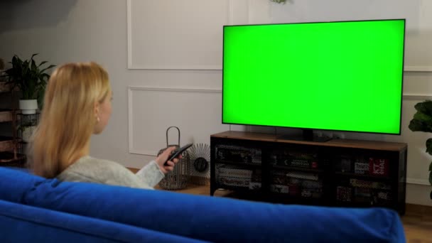 Γυναίκα κοιτάζοντας πράσινο οθόνη TV chroma κλειδί mock up κανάλια αλλαγή οθόνης - Πλάνα, βίντεο