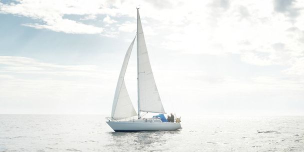 White sloop rigged yacht sailing in an open sea. Clear sky, cloudscape. A view from the sailboat. Transportation, travel, sport, recreation, leisure activity, racing, regatta. Panorama, copy space - Photo, Image