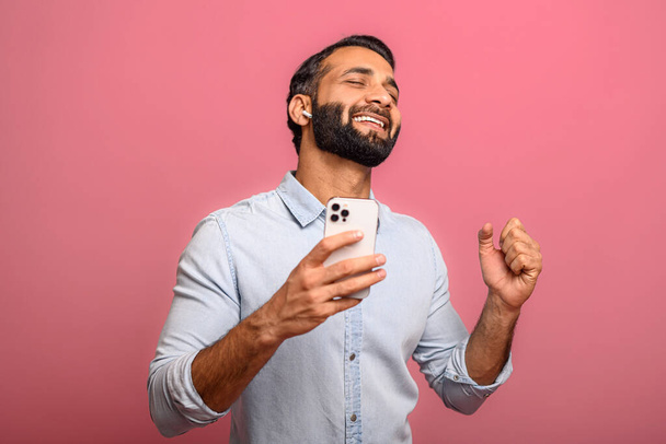 Excited multiracial manholding smartphone and rejoicing isolated on pink - 写真・画像