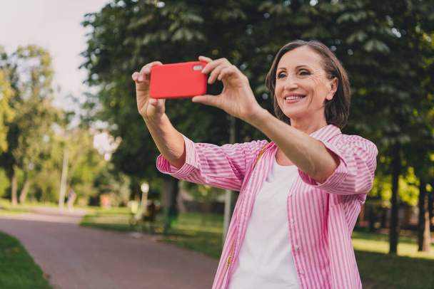 Portrait of cheerful nice person hold telephone take selfie photo good mood spend pastime park outside - Фото, зображення