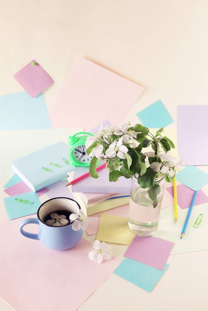 Back to school, alarm clock, apple tree flowers bouquet, stack of books, cup of tea, and stationery on the table, education, vacation time - Photo, image