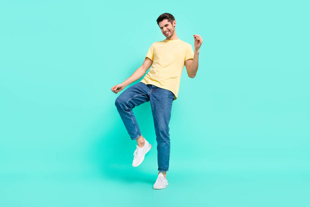 Full body photo of cool brunet guy dance wear t-shirt jeans shoes isolated on turquoise background - Fotografie, Obrázek