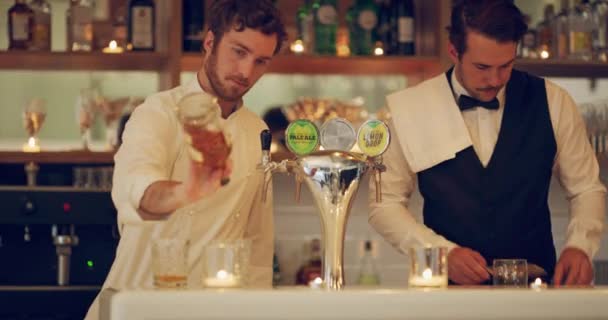 Drankjes mixen is waar we goed in zijn. 4k video-opnames van twee jonge mannen bereiden drankjes in een bar. - Video