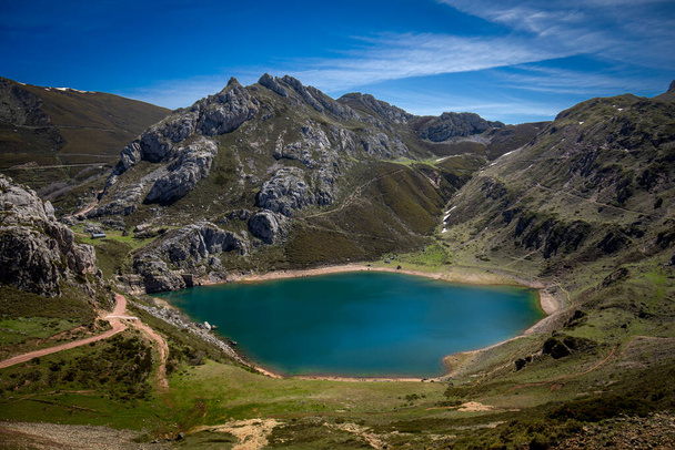 Panoramic view of the colorful Lago de la Cueva in the Parque Natural de Somiedo, in Asturias, Spain, with the snow-capped mountains in the background and green meadows. Ideal place for hiking and enjoying nature. - Photo, Image