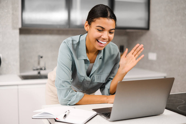 Happy young nice woman looking at laptop screen, holding video call meeting conversation, discussing working issues, passing job interview from home - Foto, Imagen