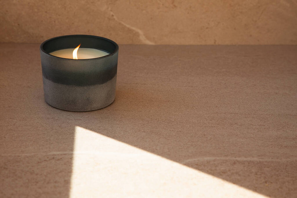 A large candle on a light beige stone background, front view - Photo, Image