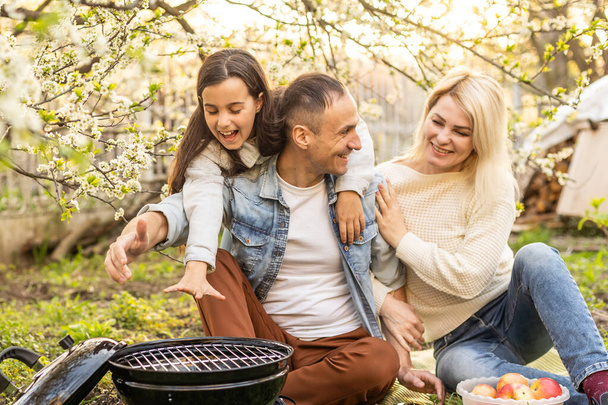 smiling parent grilling meat with daughter on camping - Fotografie, Obrázek