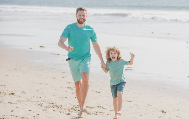 Father and son running on summer beach. Dad and child enjoying outdoor. Lifestyle and family vacation, happiness men concept. - Zdjęcie, obraz