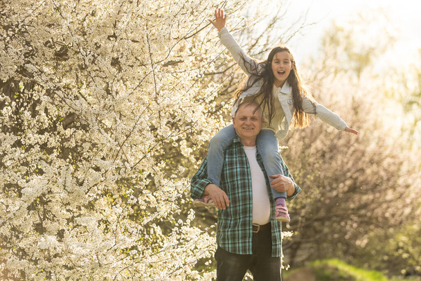 grandfather and granddaughter in a flowering garden - Photo, image
