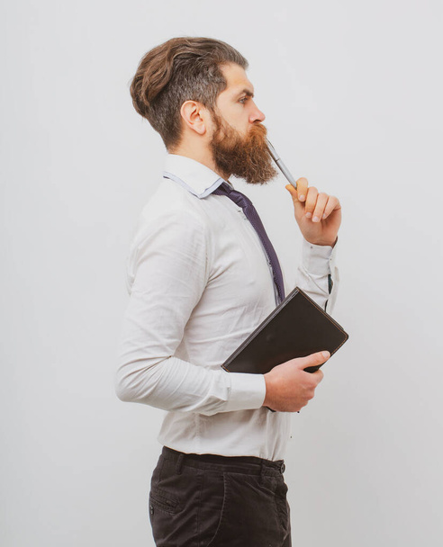 Concentrated man with pen in his mouth. Male with notepad for writing. Businessman holds notepad and pen. - Φωτογραφία, εικόνα