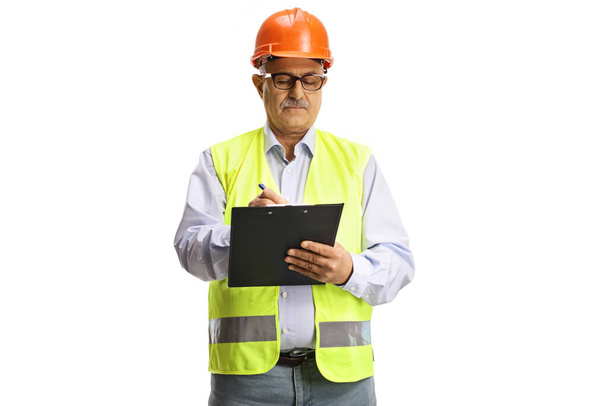 Mature male engineer with a safety vest writing a document isolated on white background - Valokuva, kuva