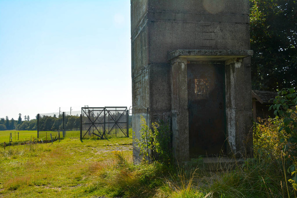 Parte inferior de una antigua torre de vigilancia fronteriza con una puerta de entrada oxidada en una antigua fortificación fronteriza de la RDA, en la esquina de tres países de Hesse, Turingia y Baviera, no lejos del moro negro en el Rhn, Alemania,  - Foto, imagen