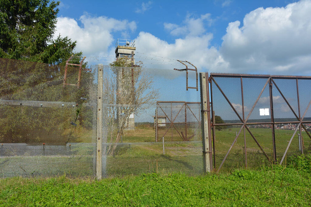 Barbed wire fence and a border watchtower on a former GDR border fortification, at the three-country corner of Hesse, Thuringia and Bavaria, not far from the Black Moor in the Rhoen, Germany, reminds of the division of Germany - Foto, Imagem