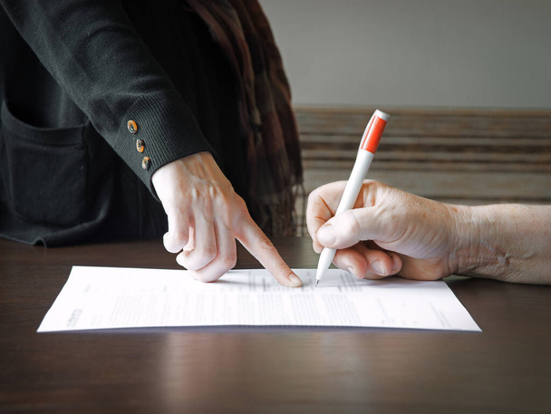 An old woman is forced to write a will for an apartment - Foto, afbeelding