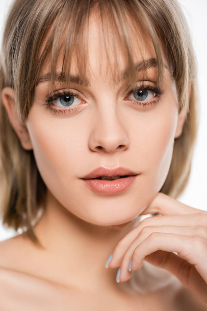 close up view of young woman with bangs and blue eyes looking at camera isolated on white - Foto, afbeelding