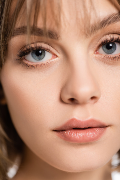 close up view of young woman with bangs and blue eyes looking at camera - 写真・画像
