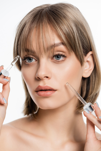 young woman with blue eyes applying serum with pipettes isolated on white - Foto, Bild